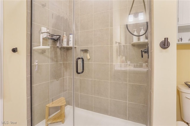 bathroom featuring a shower with shower door and toilet