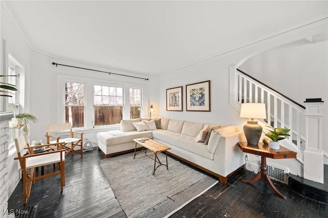 living room featuring hardwood / wood-style flooring, ornamental molding, and a brick fireplace