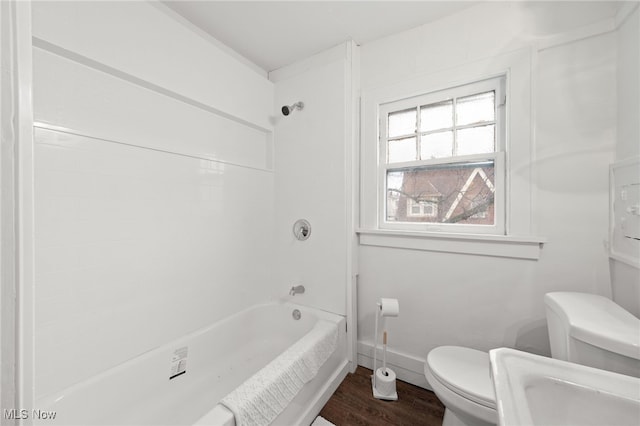 bathroom featuring hardwood / wood-style flooring, washtub / shower combination, and toilet