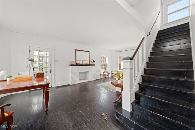 stairway featuring a fireplace, wood-type flooring, ornamental molding, and a wealth of natural light