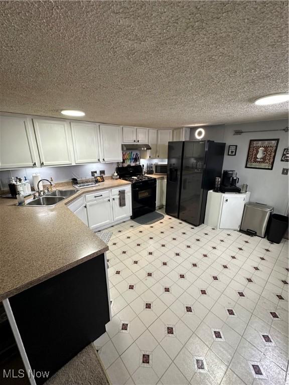 kitchen with white cabinetry, sink, black appliances, and a textured ceiling