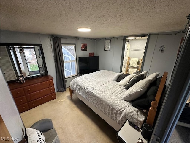 bedroom with a textured ceiling and light colored carpet