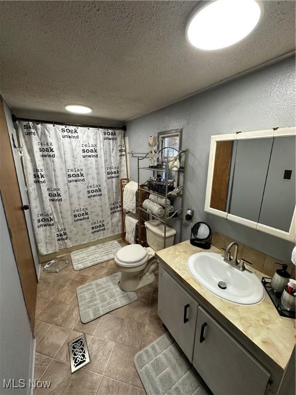 bathroom featuring vanity, a shower with shower curtain, a textured ceiling, and toilet