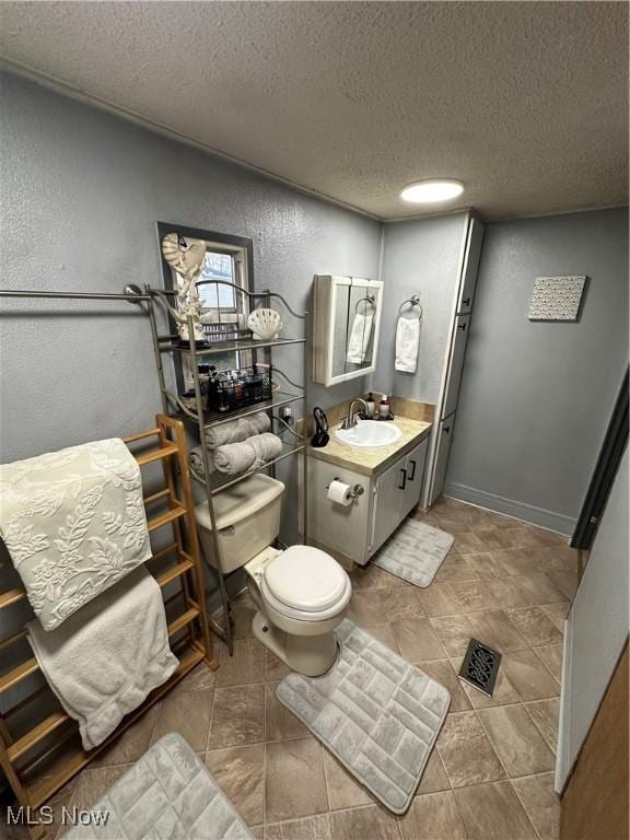 bathroom with vanity, a textured ceiling, and toilet