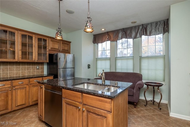 kitchen with sink, stainless steel fridge, dishwasher, tasteful backsplash, and an island with sink