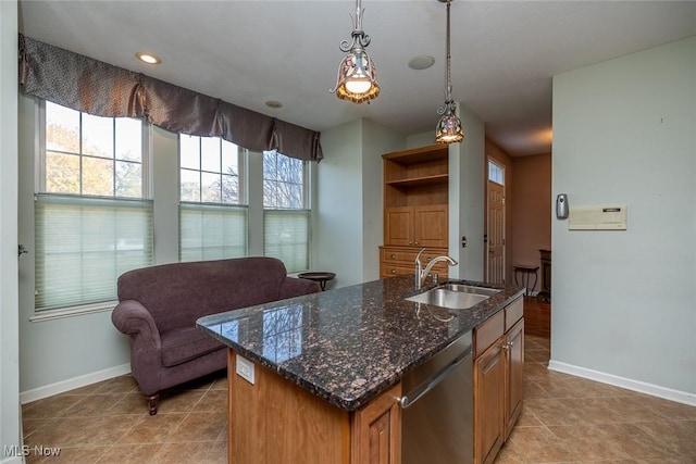 kitchen with pendant lighting, sink, dishwasher, a kitchen island with sink, and dark stone countertops