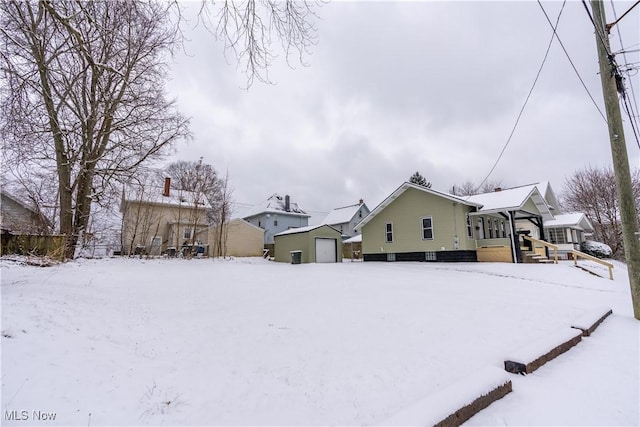 yard layered in snow featuring an outdoor structure and a garage