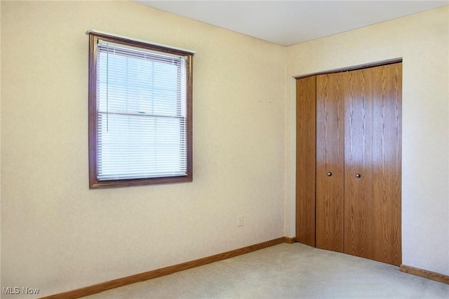 unfurnished bedroom with light carpet and a closet