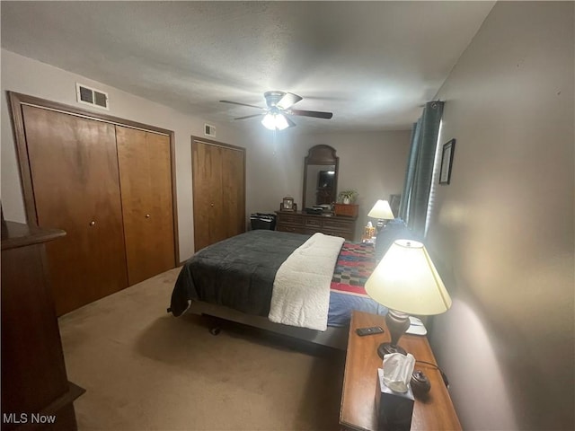 carpeted bedroom with two closets and ceiling fan