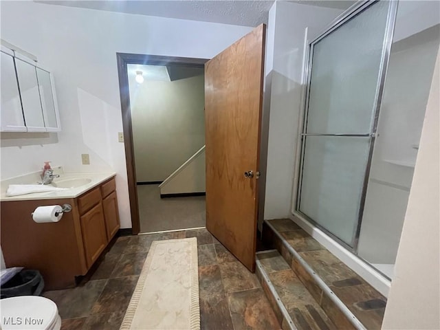 bathroom with vanity, a shower with shower door, and toilet