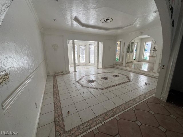 foyer entrance with a tray ceiling, a wealth of natural light, and light tile patterned floors