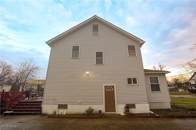 back house at dusk with a wooden deck