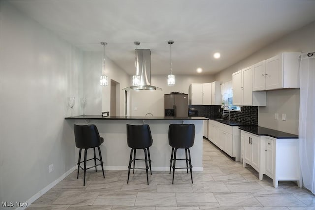 kitchen with island exhaust hood, backsplash, a breakfast bar, stainless steel fridge with ice dispenser, and white cabinetry