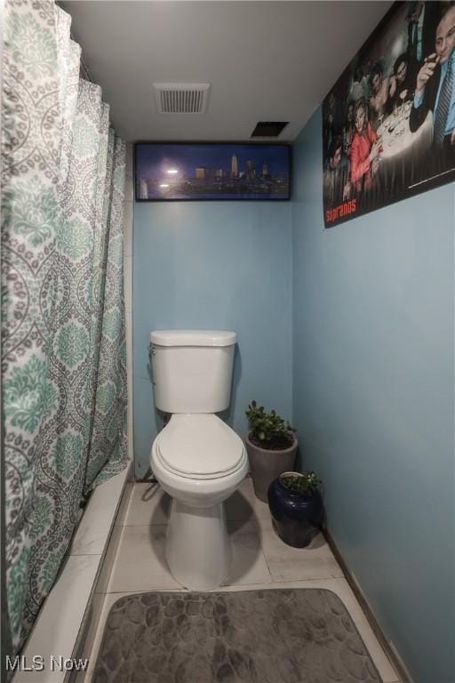 bathroom featuring a shower with shower curtain, tile patterned floors, and toilet