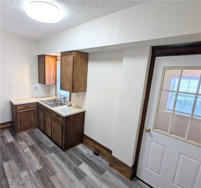 kitchen featuring decorative backsplash, hardwood / wood-style floors, a textured ceiling, and sink