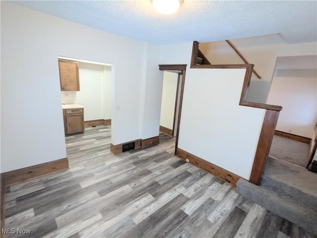 unfurnished room featuring light wood-type flooring and a textured ceiling