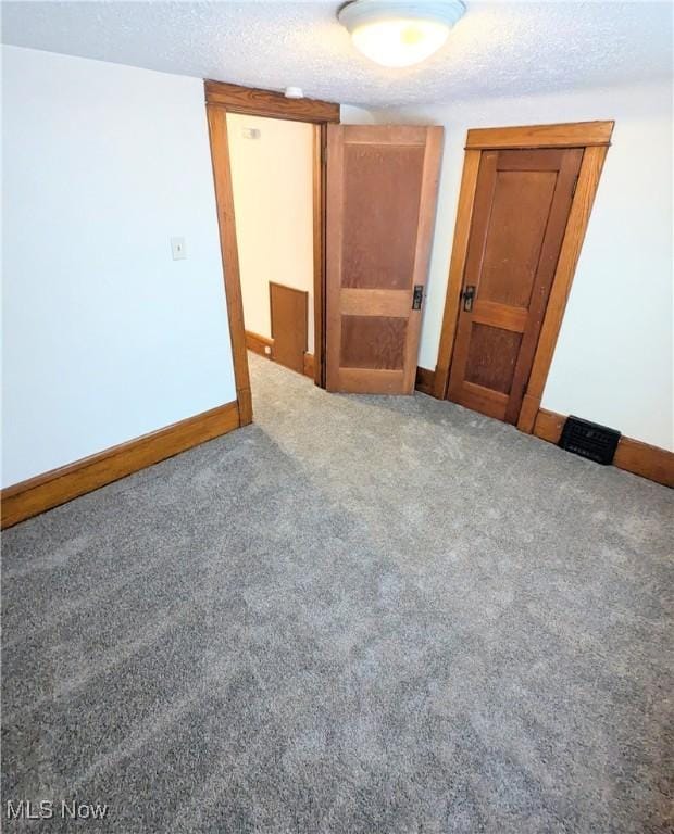 empty room with carpet floors and a textured ceiling