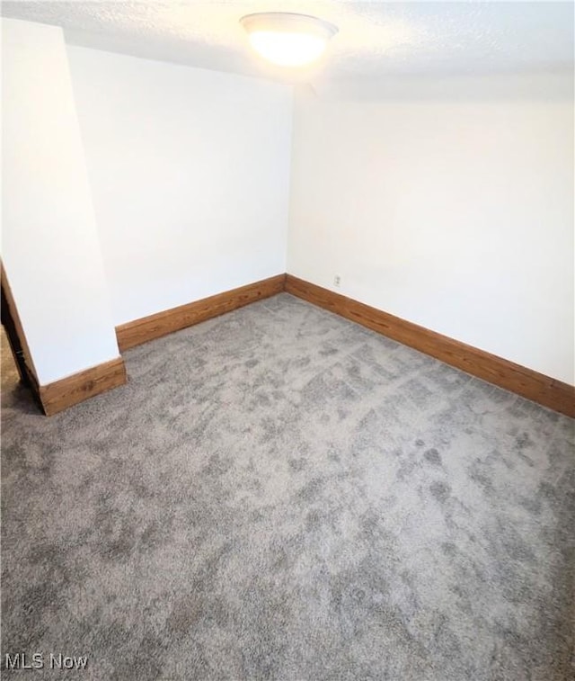 carpeted empty room featuring a textured ceiling