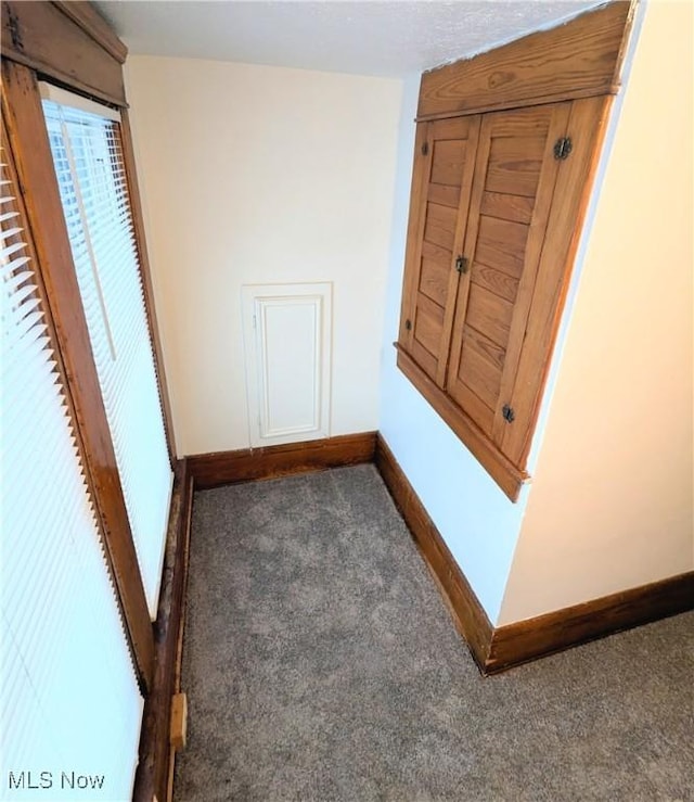 hall with dark colored carpet