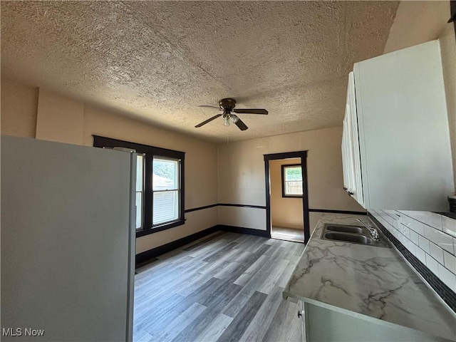 kitchen featuring white cabinets, sink, light hardwood / wood-style flooring, ceiling fan, and white fridge