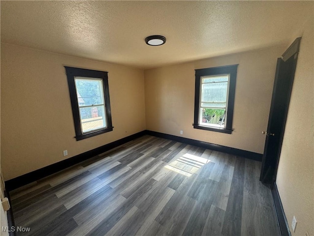 empty room featuring a textured ceiling and dark hardwood / wood-style floors