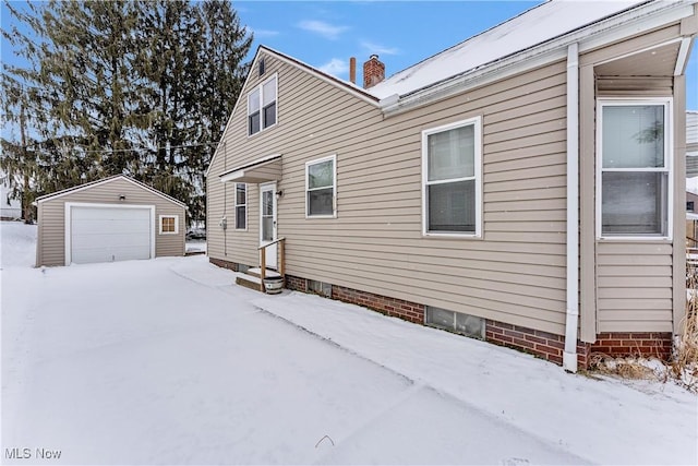 view of snow covered exterior with an outbuilding and a garage