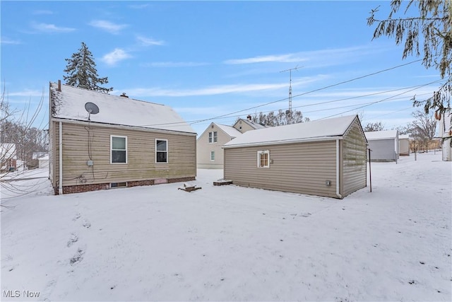 snow covered house featuring an outbuilding