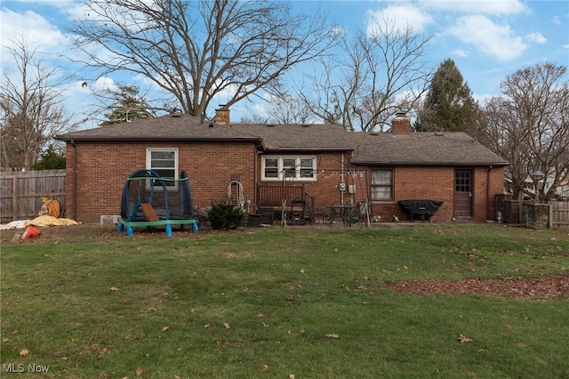 back of property with a yard and a trampoline