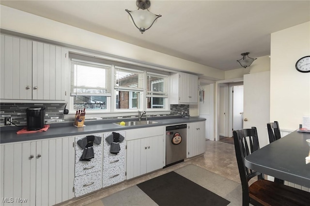 kitchen with decorative backsplash, white cabinetry, sink, and concrete floors