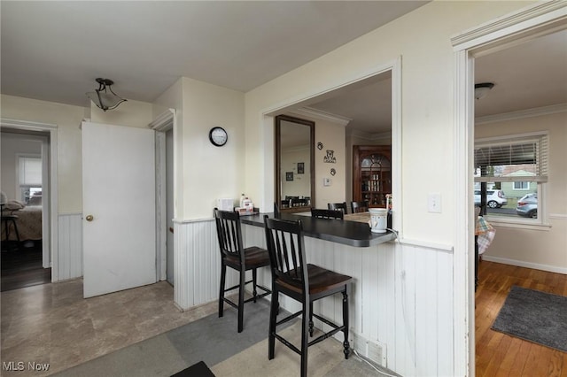 kitchen with hardwood / wood-style flooring, a breakfast bar, ornamental molding, and kitchen peninsula