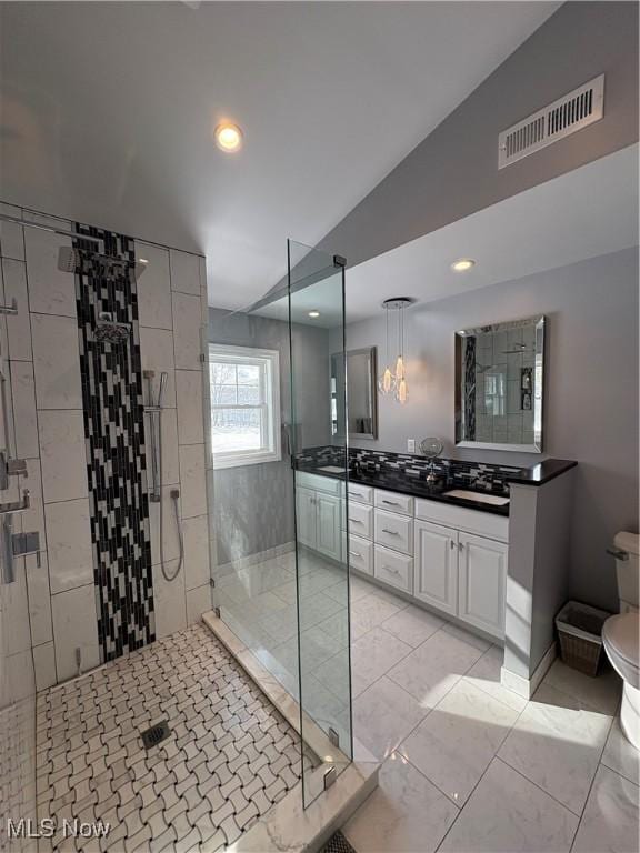 bathroom featuring vanity, toilet, a shower with shower door, and vaulted ceiling