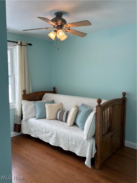 bedroom featuring ceiling fan, dark wood-type flooring, and a textured ceiling