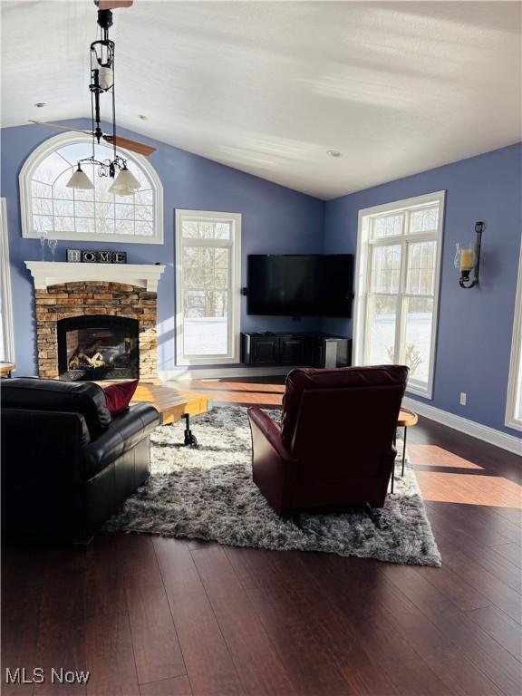 living room featuring dark hardwood / wood-style floors, lofted ceiling, a fireplace, and a wealth of natural light