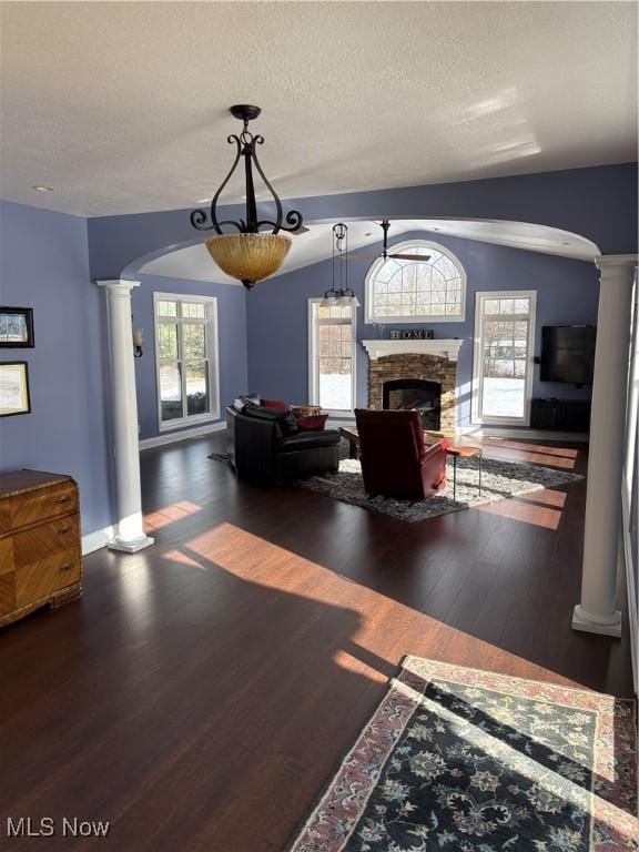 unfurnished living room featuring dark hardwood / wood-style flooring, a stone fireplace, plenty of natural light, and vaulted ceiling