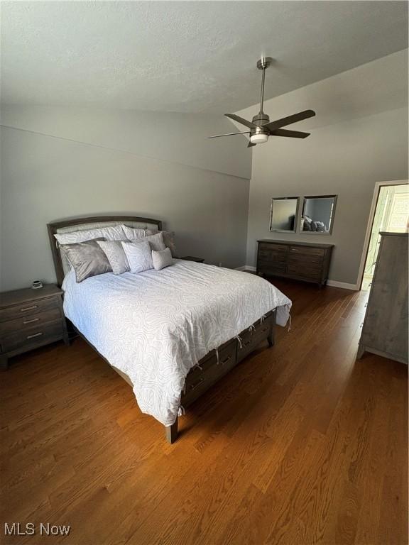 bedroom with ceiling fan, lofted ceiling, and dark wood-type flooring