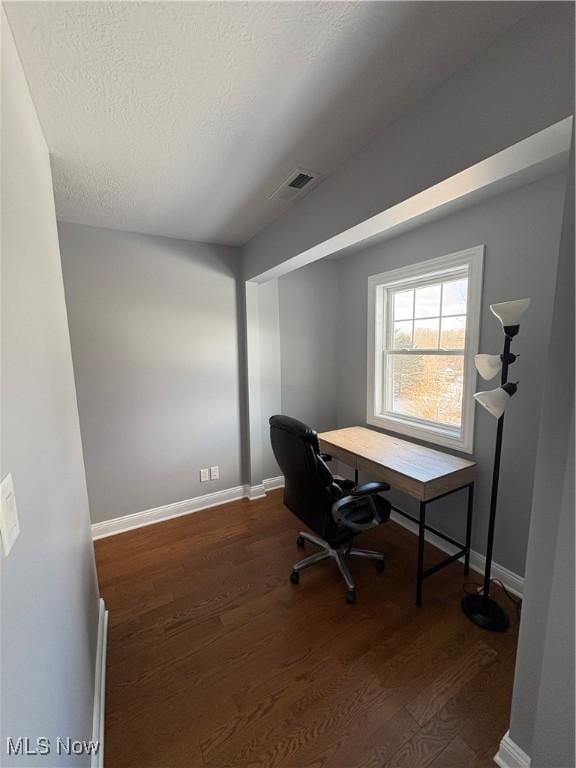 home office featuring a textured ceiling and dark wood-type flooring