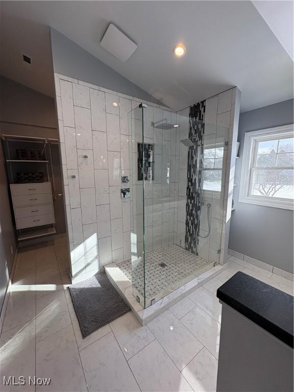 bathroom with a shower with shower door and lofted ceiling