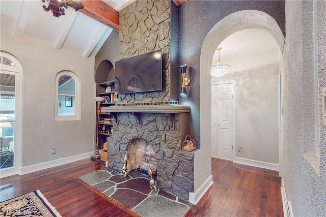 living room with a stone fireplace, lofted ceiling with beams, and dark hardwood / wood-style floors