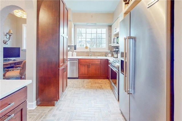 kitchen featuring backsplash, high quality appliances, and sink