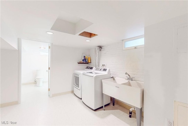 laundry area featuring independent washer and dryer, sink, and brick wall