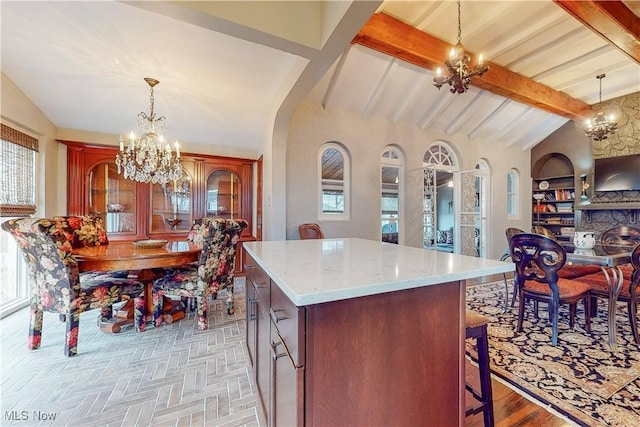 kitchen featuring vaulted ceiling with beams, a center island, hanging light fixtures, and a notable chandelier