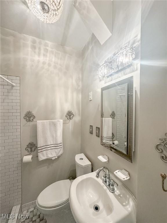 bathroom with a chandelier, tile patterned flooring, toilet, and sink