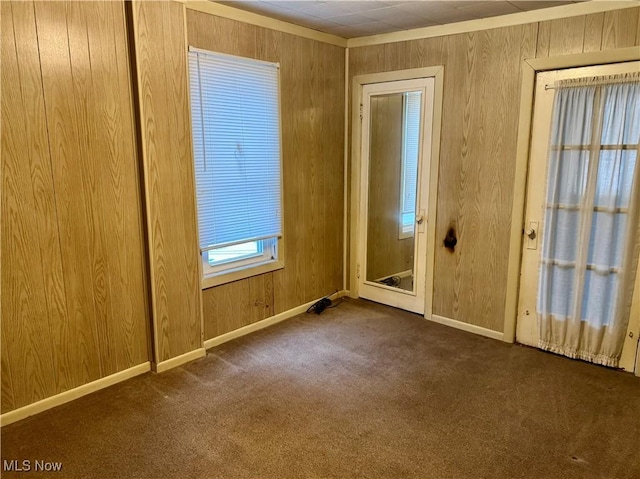 carpeted spare room with wood walls