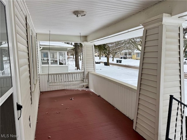 snow covered back of property with covered porch