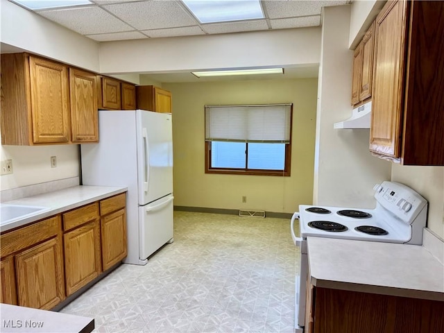 kitchen with white appliances, a drop ceiling, and sink