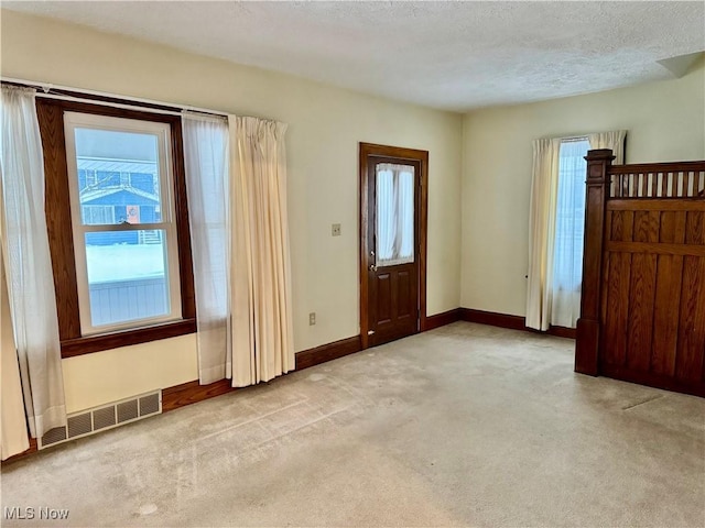 entrance foyer with light colored carpet and a textured ceiling