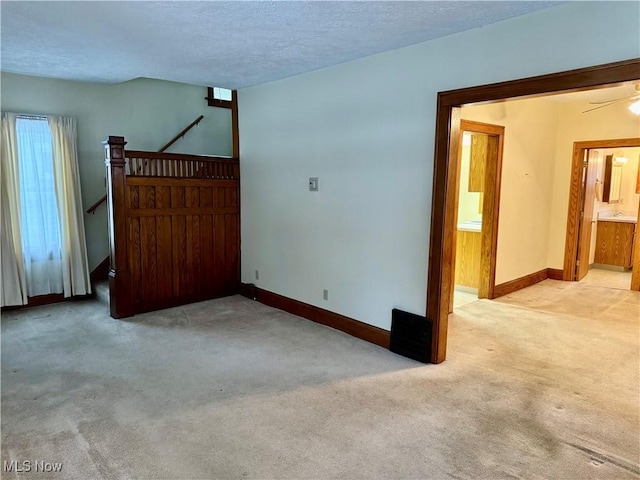 unfurnished room featuring ceiling fan, light colored carpet, and a textured ceiling