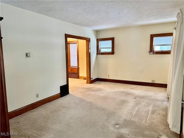 unfurnished room with a textured ceiling and light colored carpet