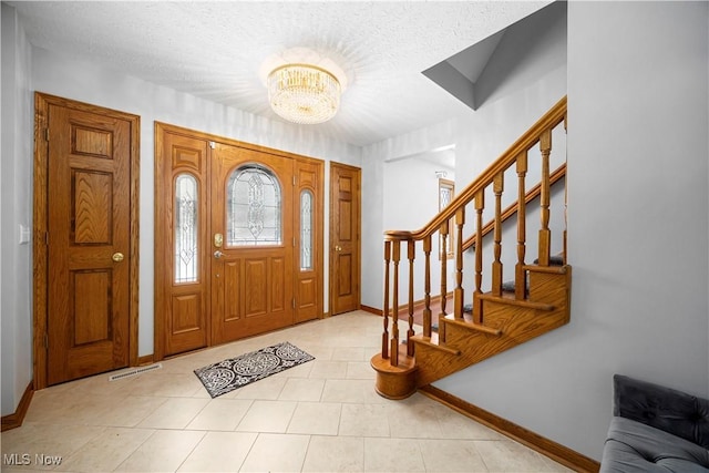 entrance foyer featuring light tile patterned floors, an inviting chandelier, and a textured ceiling