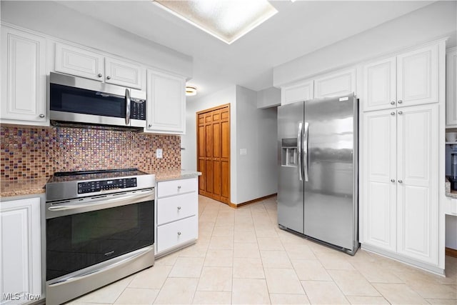 kitchen with light stone countertops, white cabinets, stainless steel appliances, tasteful backsplash, and light tile patterned floors